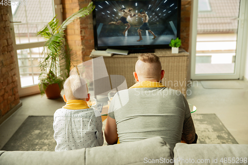 Image of Excited family watching martial arts, sport match at home, father and son