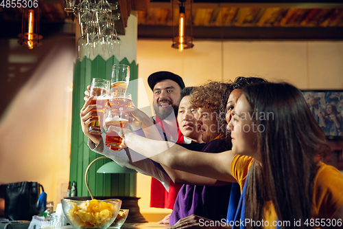 Image of Sport fans cheering at bar, pub and drinking beer while championship, competition is going