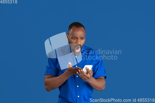 Image of Monochrome portrait of young african-american man on blue studio background