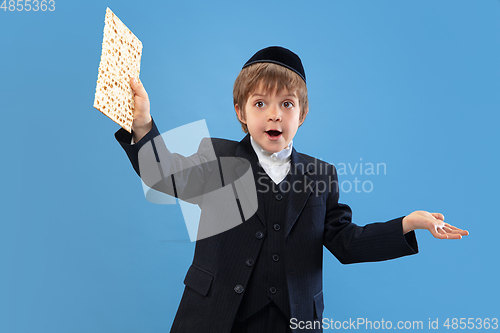 Image of Portrait of a young orthodox jewish boy isolated on blue studio background, meeting the Passover