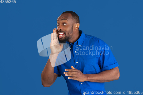 Image of Monochrome portrait of young african-american man on blue studio background