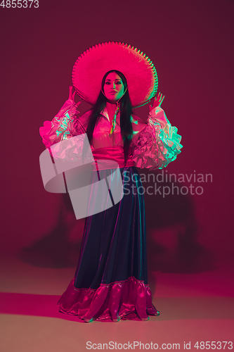 Image of Fabulous Cinco de Mayo female dancer on purple studio background in neon light