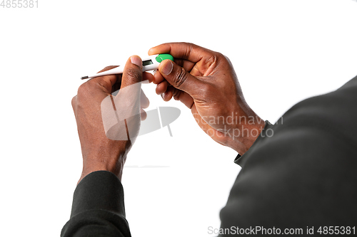 Image of How coronavirus changed our lives. Close up of male hands holding thermometer, taking temperature on white background