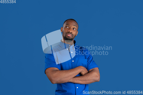 Image of Monochrome portrait of young african-american man on blue studio background