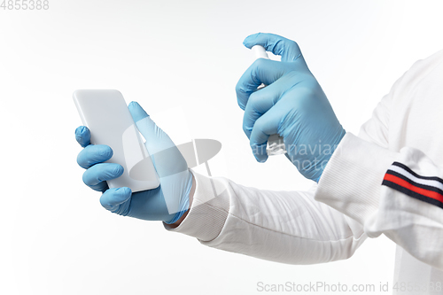 Image of How coronavirus changed our lives. Young man disinfecting gadgets surfaces on white background