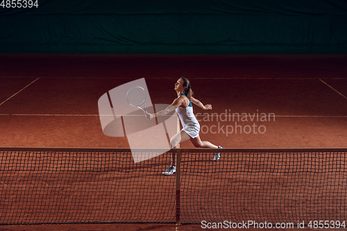 Image of Young caucasian professional sportswoman playing tennis on sport court background