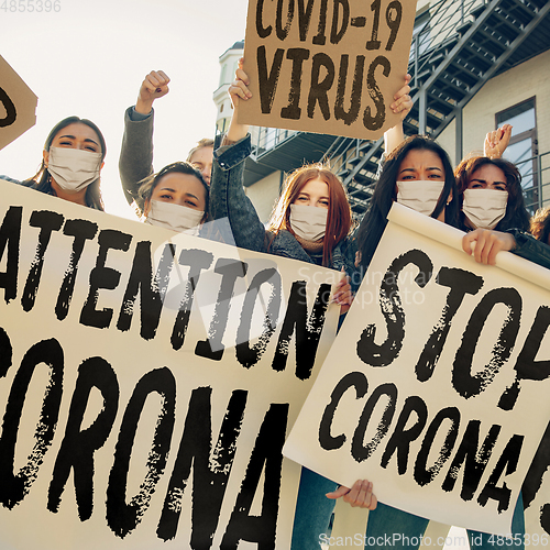 Image of Young people in face masks protesting of stop coronavirus pandemic on the street