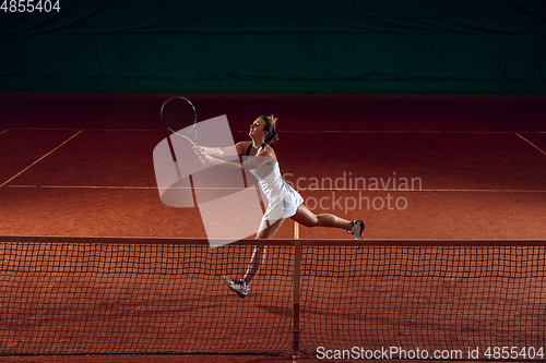 Image of Young caucasian professional sportswoman playing tennis on sport court background