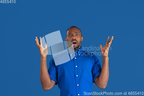 Image of Monochrome portrait of young african-american man on blue studio background