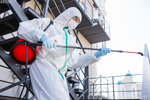 Image of Coronavirus Pandemic. A disinfector in a protective suit and mask sprays disinfectants in the house or office