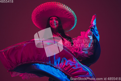 Image of Fabulous Cinco de Mayo female dancer on purple studio background in neon light