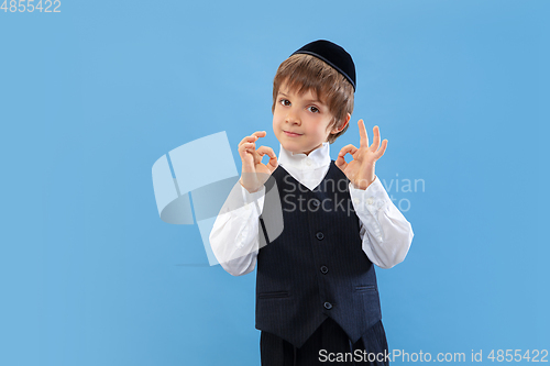 Image of Portrait of a young orthodox jewish boy isolated on blue studio background, meeting the Passover