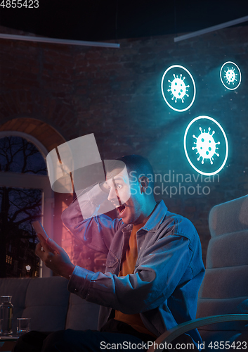 Image of Shocked, upset and sad man using gadgets to get information of coronavirus pandemic spread