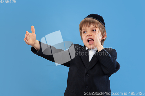 Image of Portrait of a young orthodox jewish boy isolated on blue studio background, meeting the Passover