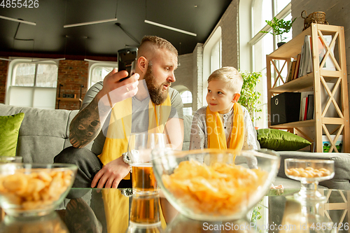 Image of Excited family watching football, sport match at home, father and son