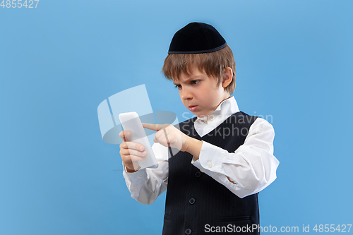 Image of Portrait of a young orthodox jewish boy isolated on blue studio background, meeting the Passover