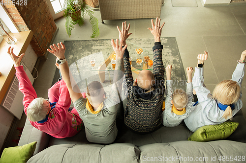 Image of Excited family watching football, sport match at home, top view