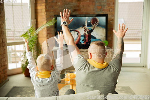 Image of Excited family watching basketball, sport match at home, father and son