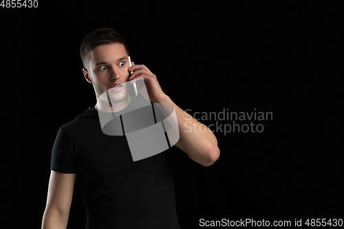 Image of Monochrome portrait of young caucasian man on black studio background
