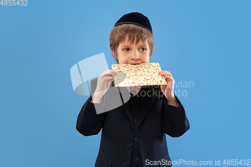 Image of Portrait of a young orthodox jewish boy isolated on blue studio background, meeting the Passover