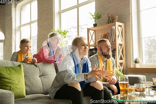 Image of Excited family watching football, sport match at home, top view