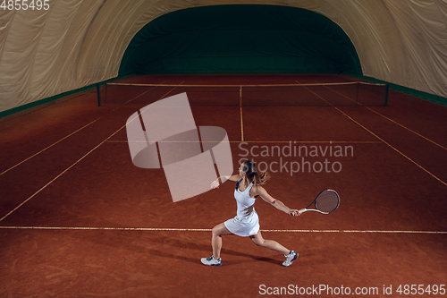 Image of Young caucasian professional sportswoman playing tennis on sport court background