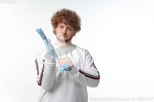 Image of How coronavirus changed our lives. Young man holding thermometer, taking temperature on white background