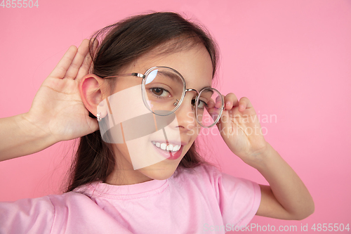 Image of Caucasian little girl portrait isolated on pink studio background, emotions concept