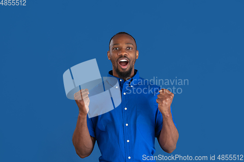 Image of Monochrome portrait of young african-american man on blue studio background