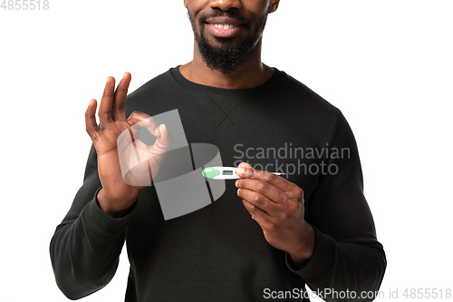 Image of How coronavirus changed our lives. Young man checking, taking temperature on white background