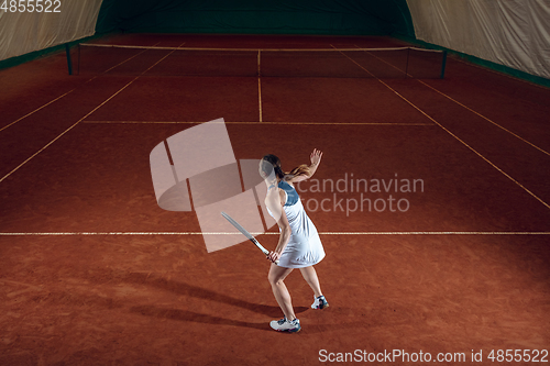 Image of Young caucasian professional sportswoman playing tennis on sport court background