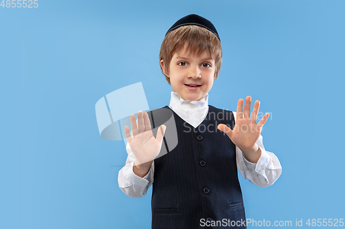 Image of Portrait of a young orthodox jewish boy isolated on blue studio background, meeting the Passover