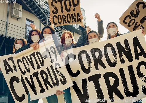 Image of Young people in face masks protesting of stop coronavirus pandemic on the street