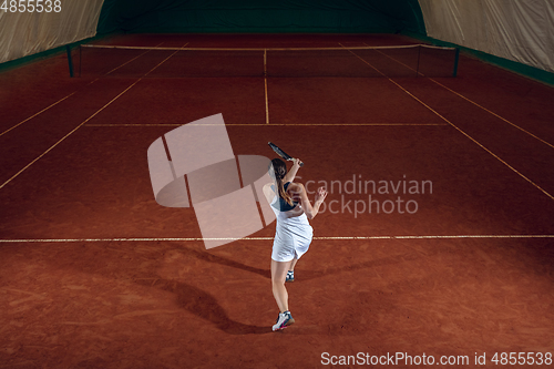 Image of Young caucasian professional sportswoman playing tennis on sport court background