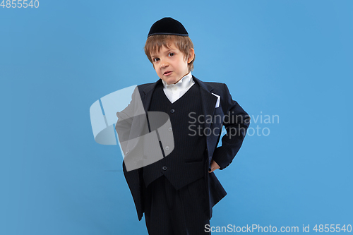 Image of Portrait of a young orthodox jewish boy isolated on blue studio background, meeting the Passover