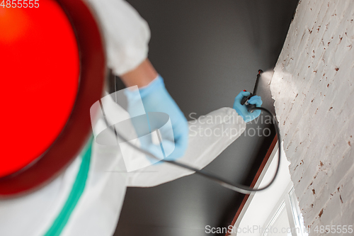 Image of Coronavirus Pandemic. A disinfector in a protective suit and mask sprays disinfectants in the house or office