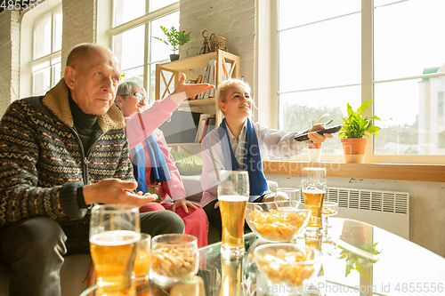 Image of Excited family watching football, sport match at home, top view