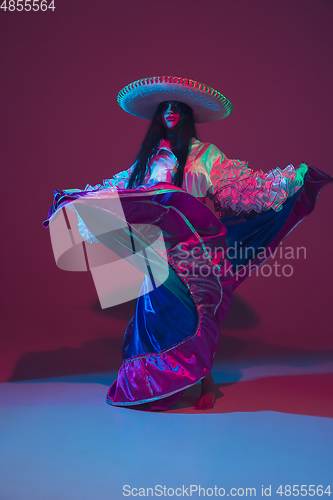 Image of Fabulous Cinco de Mayo female dancer on purple studio background in neon light