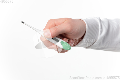 Image of How coronavirus changed our lives. Close up of male hands holding thermometer, taking temperature on white background