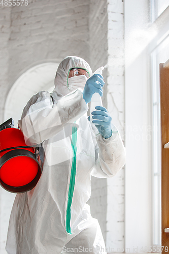 Image of Coronavirus Pandemic. A disinfector in a protective suit and mask sprays disinfectants in the house or office