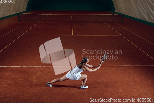 Image of Young caucasian professional sportswoman playing tennis on sport court background