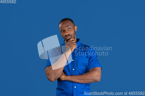 Image of Monochrome portrait of young african-american man on blue studio background