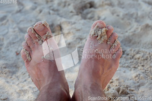 Image of mans feet on sand beach