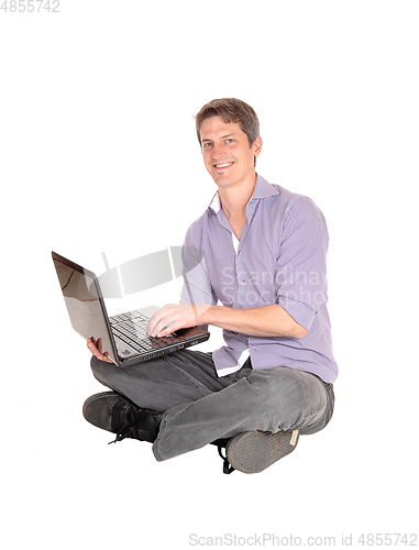 Image of Man working on laptop on the floor