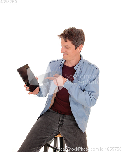 Image of Young man sitting on chair pointing to his tablet
