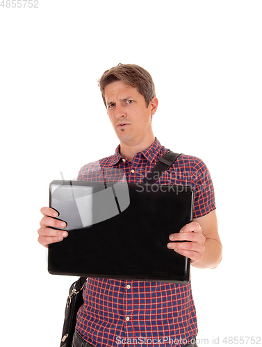 Image of Puzzled man holding up his laptop to see