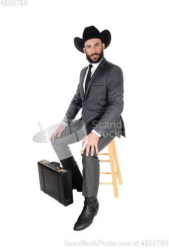 Image of Business man sitting with hat and briefcase