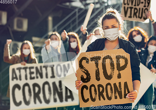 Image of Young people in face masks protesting of stop coronavirus pandemic on the street