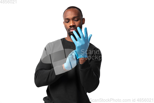 Image of How coronavirus changed our lives. Young man holding thermometer, taking temperature on white background