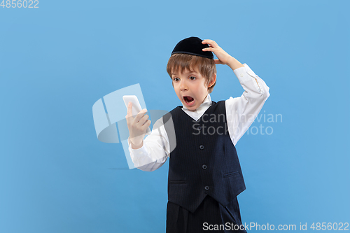 Image of Portrait of a young orthodox jewish boy isolated on blue studio background, meeting the Passover